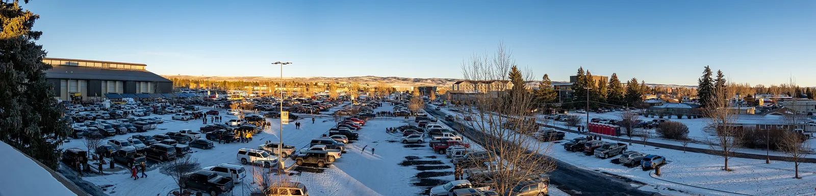 Hundreds of cars and canopies filling a stadium parking lot before a college game.