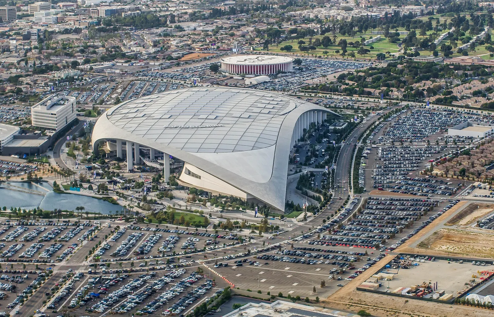 SoFi Stadium on game day with packed parking lots and the Forum in the background.